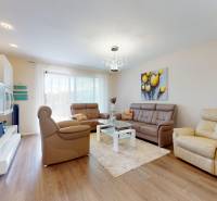 Living room with leather sofas, a table, and a wooden decor floor in a family house.