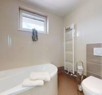 A bathroom in a family house with a bathtub, a window, and a ladder radiator.