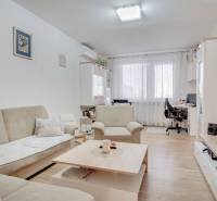 Living room in a three-room apartment with a wooden decor floor and comfortable seating.