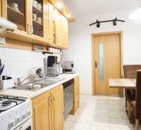 A kitchen in a 3-room apartment with wooden cabinets and a dining table.