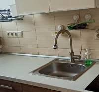 A kitchen in a 2-room apartment with a sink, a ceramic hob, and a basket by the window.