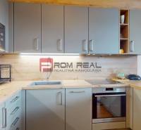 A kitchen with wood decor flooring, built-in appliances, and wall cabinets in a 2-room apartment.