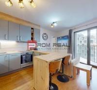 A kitchen in a 2-room apartment with a wooden decor floor and a large balcony window.