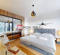 Bedroom in a 2-room apartment, with a double bed and a wooden decor floor.