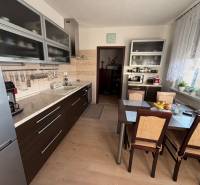A kitchen in a 3-room apartment with a kitchen unit and a table, floor with wooden decor.