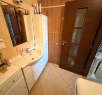 A bathroom in a 3-room apartment with white furniture and dark doors.