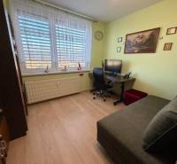 A room with a wooden decor floor in a 3-room apartment, equipped with a sofa and a desk.