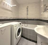 Bathroom with a bathtub, washing machine, and tiles in a 2-room apartment.