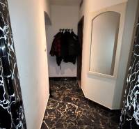 A hallway in a family house with a marble floor, a mirror, and coat hooks.