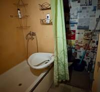 A bathroom with a bathtub and a green curtain in a studio apartment.
