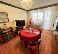 Dining area in a 3-room apartment with a red tablecloth and large windows.