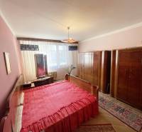 A bedroom in a 3-room apartment with red bedding and wooden wardrobes.