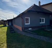 A family house in Mýtne Ludany, surrounded by a garden, with a blue sky and sunshine.