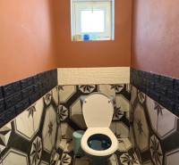 A bathroom in a family house with striking geometric tiles and orange walls.