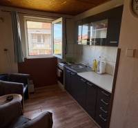 A kitchen with a wood-patterned floor and dark cabinets in a family house.