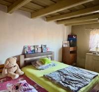 A bedroom in a family house with a wooden ceiling, a bed, and a plush teddy bear.
