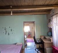 A room with a wooden floor decor, a bed, a work desk, and decorative beams on the ceiling.
