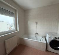 A bathroom in a 3-room apartment with a bathtub, washing machine, and a large window.