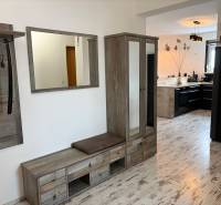 A hallway with wooden decor and a view into the kitchen in a 3-room apartment.