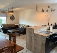 Kitchen with dining area in a 3-room apartment, floor with wood decor, comfortable sofa.