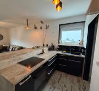 A kitchen with black furniture, a bar counter, and a wooden decor floor in a 3-room apartment.