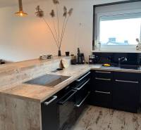 A kitchen in a 3-room apartment with black cabinets and a wooden decor floor.