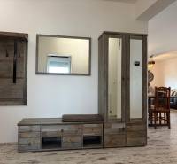 A hallway in a 3-room apartment with a coat rack and a wardrobe, floor with a wooden decor.