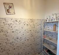 A room with wallpaper imitating bricks, a shelf with supplies and decorations.