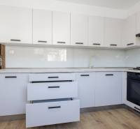 A kitchen in a 3-room apartment with white cabinets and a wood-patterned floor.