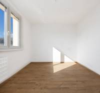 A room with a light wall and a window, a floor with a wooden decor in a 3-room apartment.