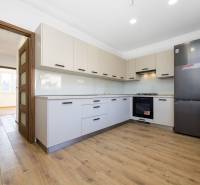 A kitchen in a 3-room apartment with a modern kitchen unit and a floor with a wood decor.