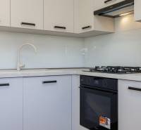 A kitchen in a 3-room apartment with a stove and white cabinets.