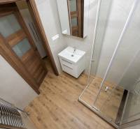 A bathroom with a bathtub, sink, and a wooden decor floor in a 3-room apartment.