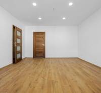 A room in a 3-room apartment with a wooden decor floor and wooden doors.