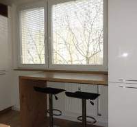 The kitchen of a three-room apartment with a wooden decor floor and large windows.