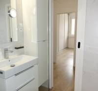 Bathroom with a sink, white cabinet, and a view into the hallway in a 3-room apartment.