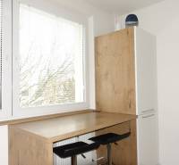 The kitchen of a three-room apartment with stools and a table with a wooden decor, sunny window.
