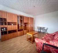 A living room in a three-room apartment with a red sofa and a wooden wall unit.