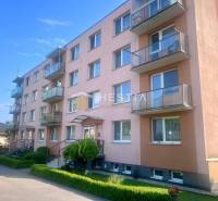 A four-story apartment building in Moravské Lieskové with balconies and parking in front of the building.