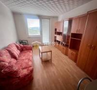 A room in a 3-room apartment with a sofa, cabinets, and a table on a light floor.