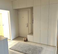 The entrance hall of a 3-room apartment with white cabinets and tiles, carpet on the floor.