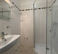 Bathroom with white tiles and a shower in a studio apartment.