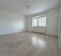A spacious room in a one-bedroom apartment with a wooden decor floor.
