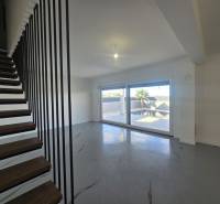 Living room in a villa with modern stairs and large windows.