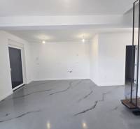 A spacious room in a villa with white walls and a gray floor with a decor.