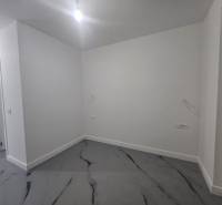 An empty room in a villa with white walls and a marble-patterned floor.