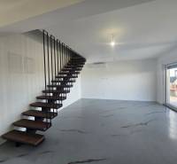 Interior of a villa with a metal staircase and a wooden decor floor, large window to the terrace.