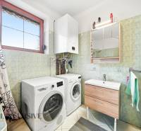 Bathroom with a washing machine, sink, and gas boiler in a family house.