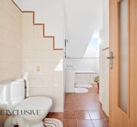 Bathroom with toilet, sink, and bathtub in a family house, floor with ceramic tiles.