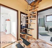 Spiral staircase, bathroom with a washing machine, and floor with wooden decor in a family house.